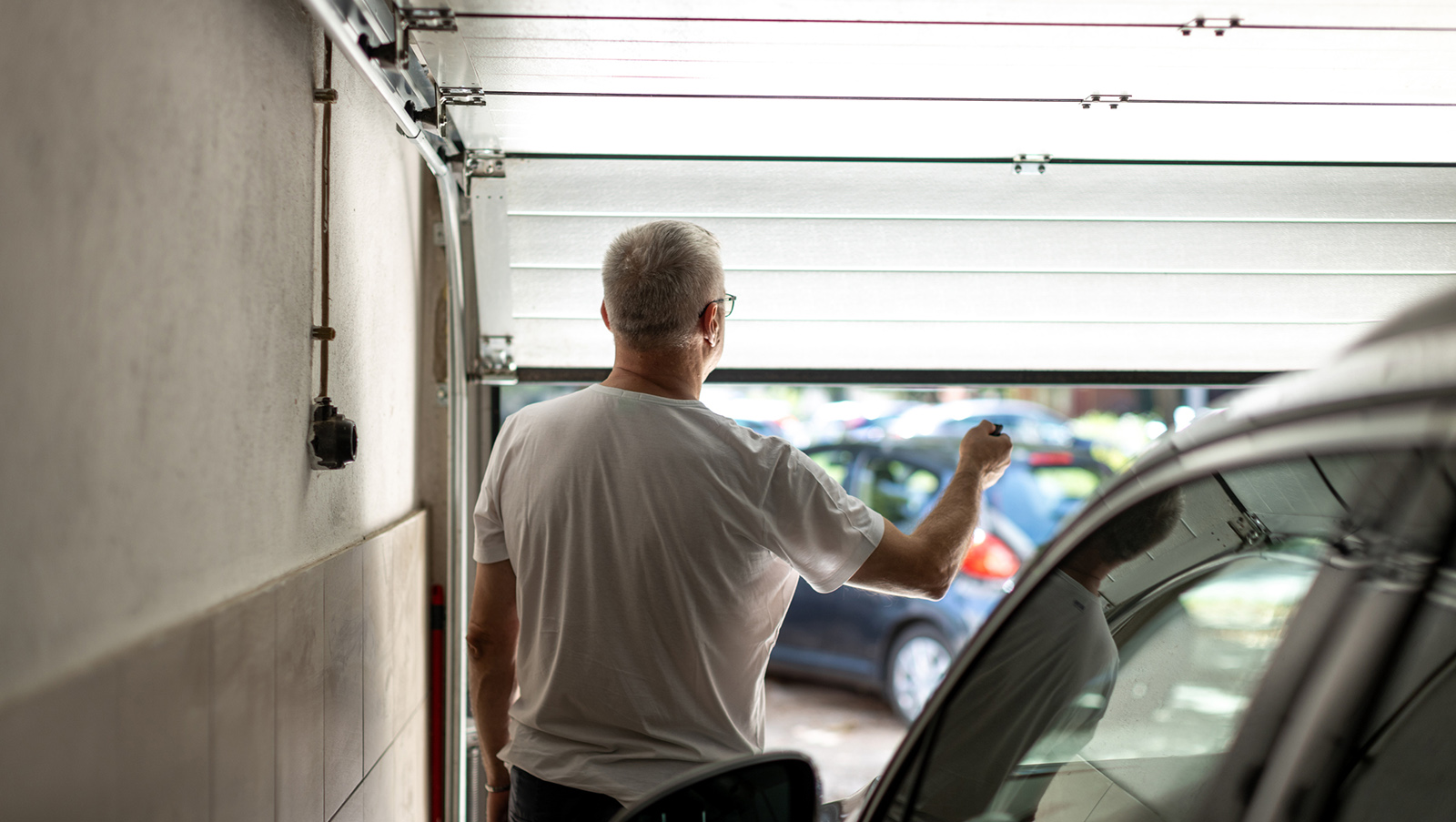 Rear view of man opening garage door
